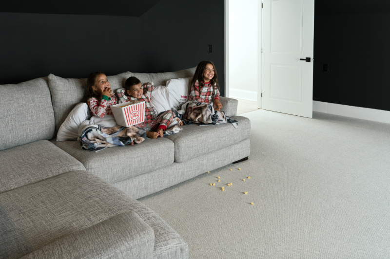 Children eating messy popcorn on a sofa on a durable carpet