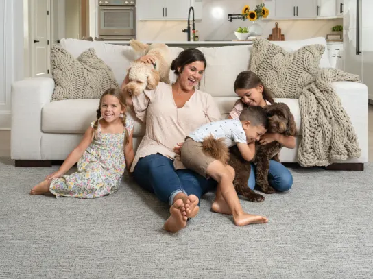 Mother and children playing with family dog on a durable carpet floor