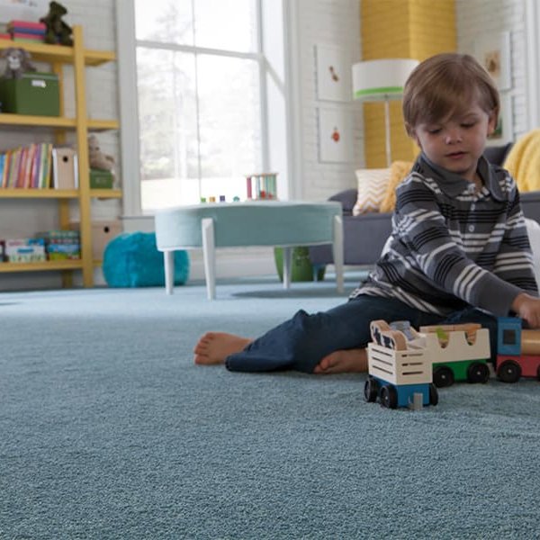 Child playing on a blue durable carpet in Dayton, OH by Bockrath Flooring and Rugs